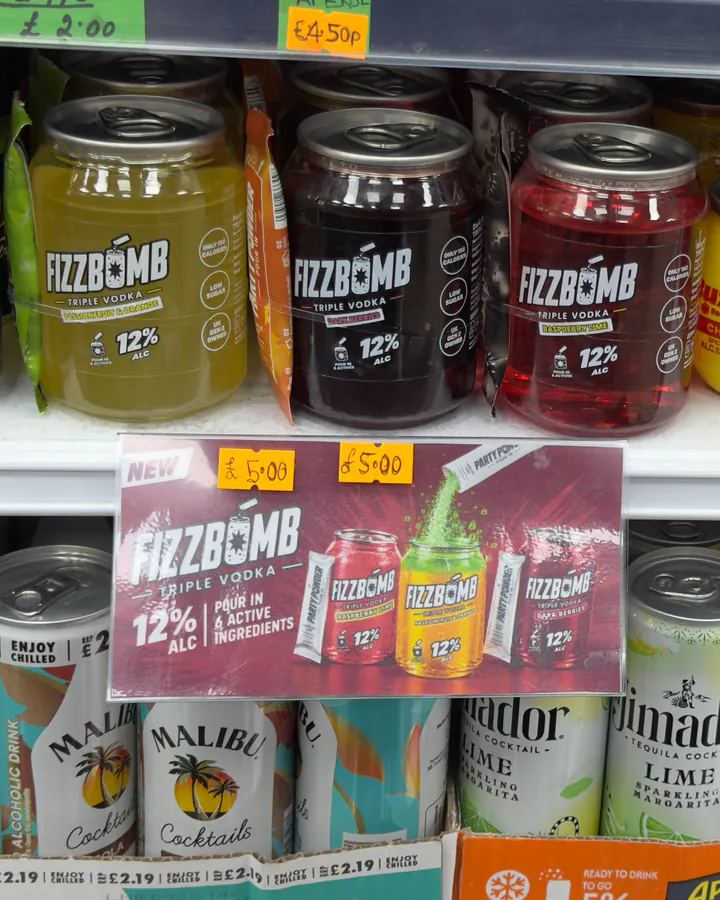 Three FizzBomb cans in a shop fridge above a “New FizzBomb” shelf card