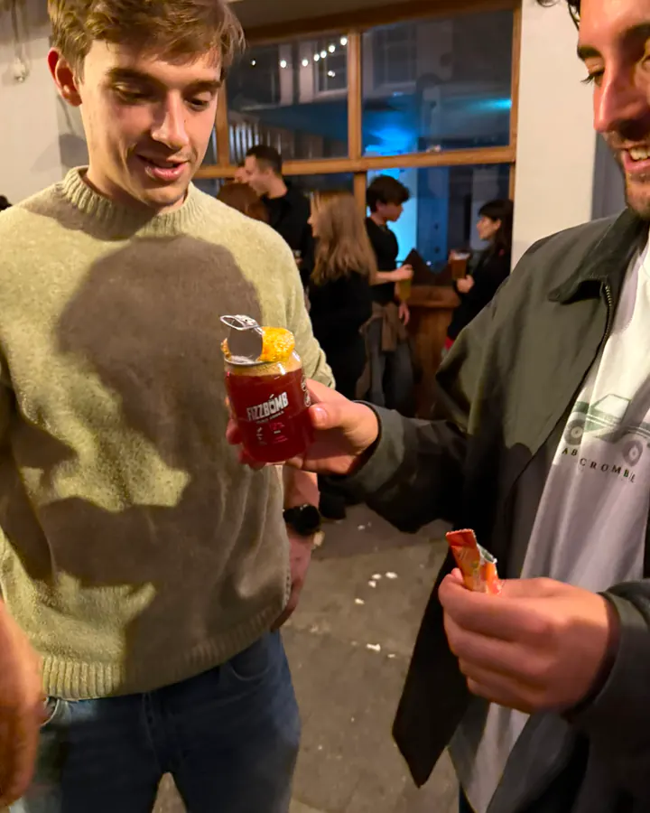 Two friends outside a pub at night, one holding out a FizzBomb can with its Party Powder poured in