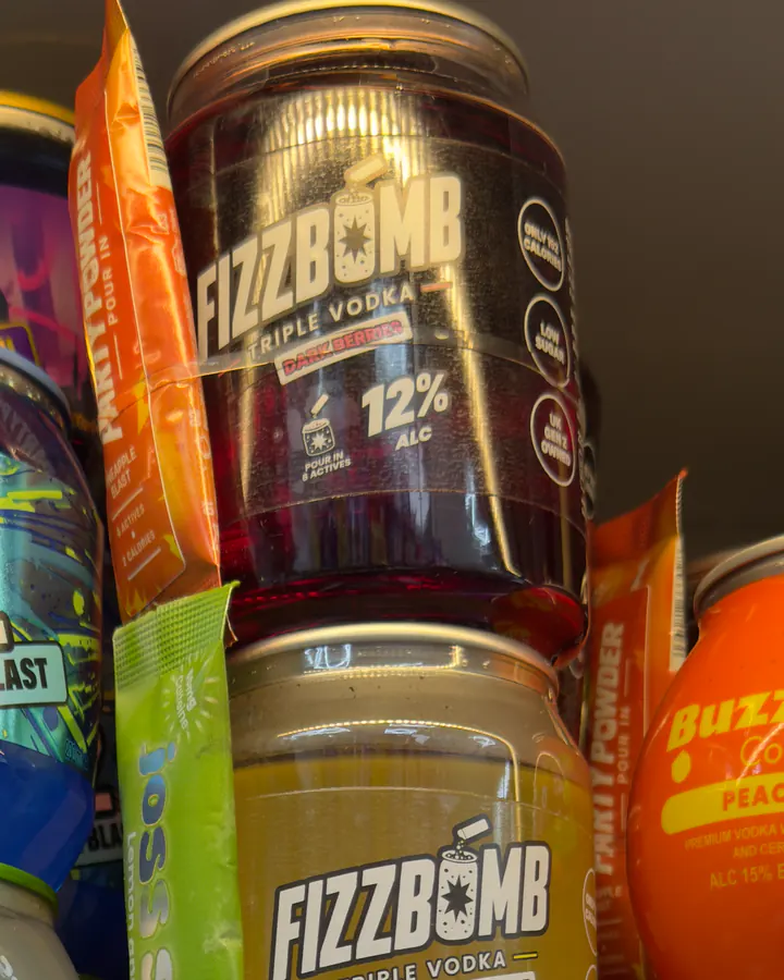 FizzBomb cans stacked on a shop shelf with their Party Powder sachets
