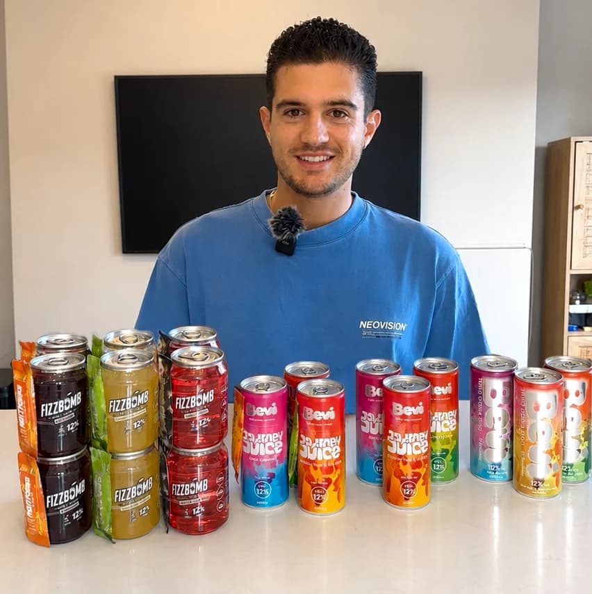 Josh, FizzBomb's founder, behind a table of every can so far: FizzBomb, Journey Juice and the original Bevi