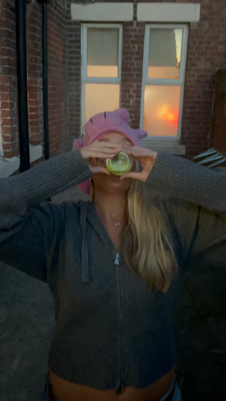 A friend in a pink knitted pig hat holding her FizzBomb can up for a sip